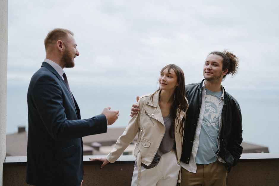 A couple thoughtfully looking at a tablet together on the patio of a modern home with an ocean view, symbolizing the decision-making process for Americans buying property in Mexico.