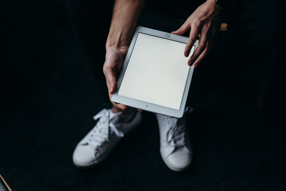 Real estate professional stands outside a modern home, analyzing property data on a digital tablet, representing the moder...